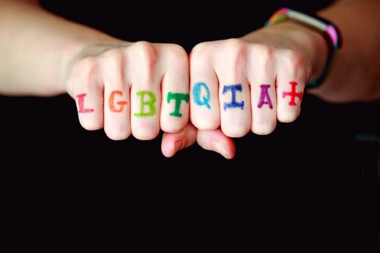 hands with colored acronym LGBTQIA+ on fingers