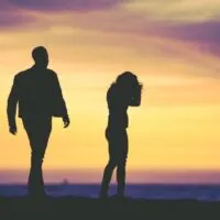black silhouettes of a couple walking on the beach