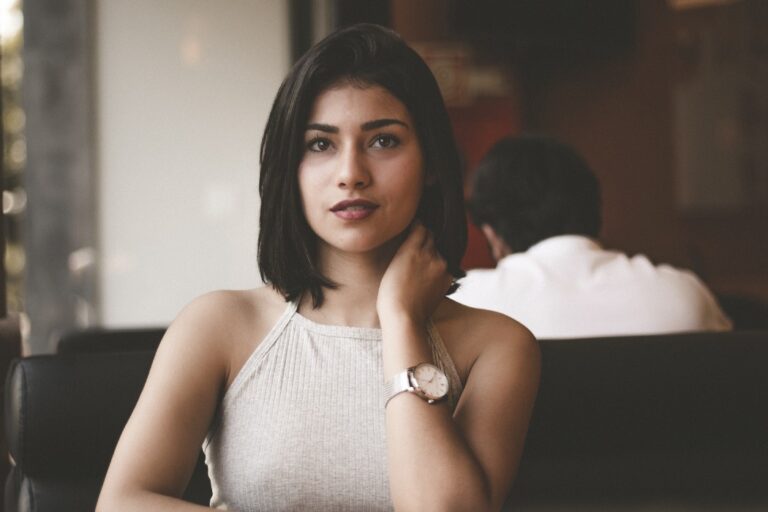girl with brown smiling and touching her neck