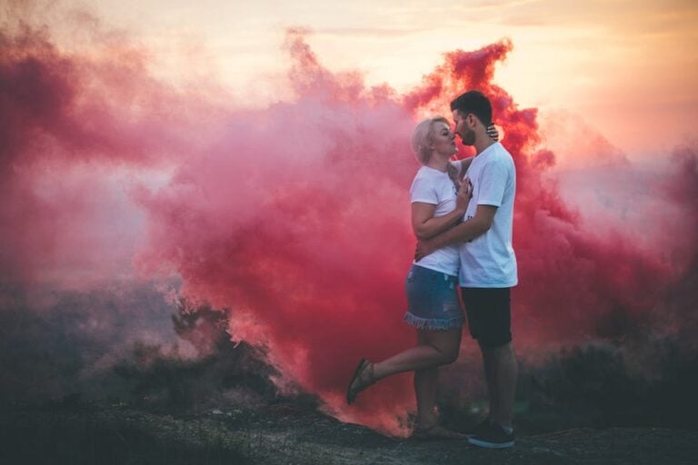 man and woman kissing in red smoke