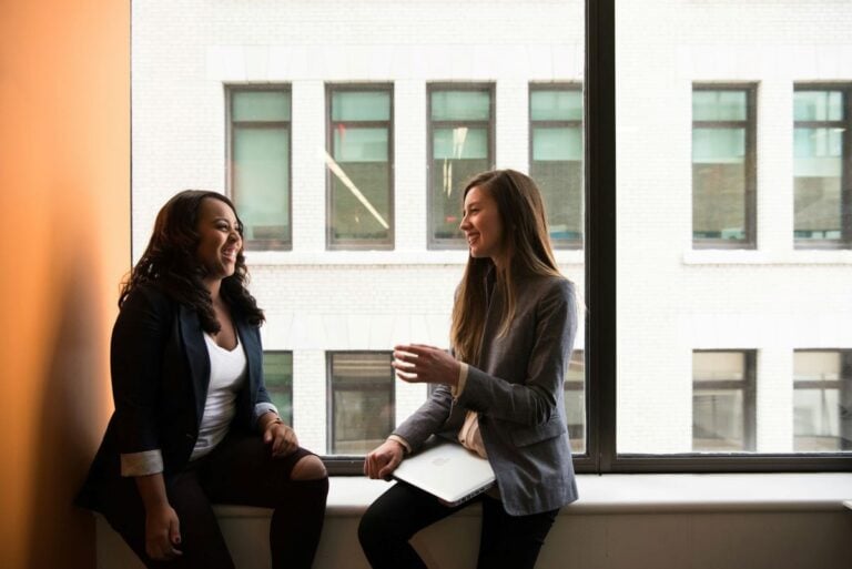 two women having in conversation in front of a window in an office