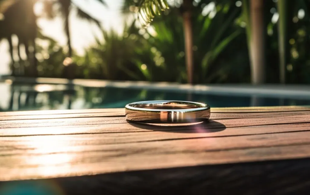 wedding rng on a wooden table, pool and palm trees in the background