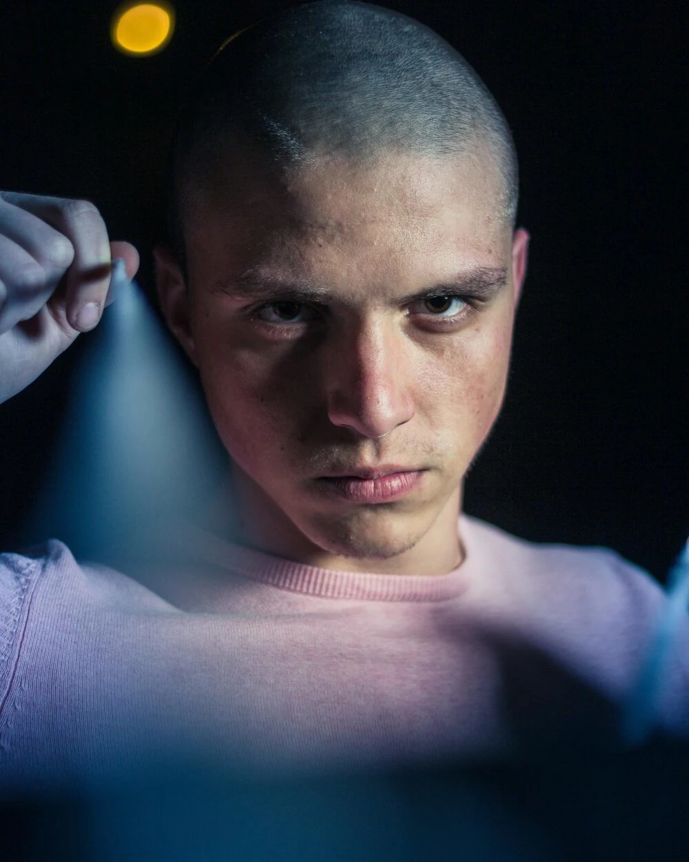 A strong portrait capturing a bald man with a serious facial expression in soft lighting.