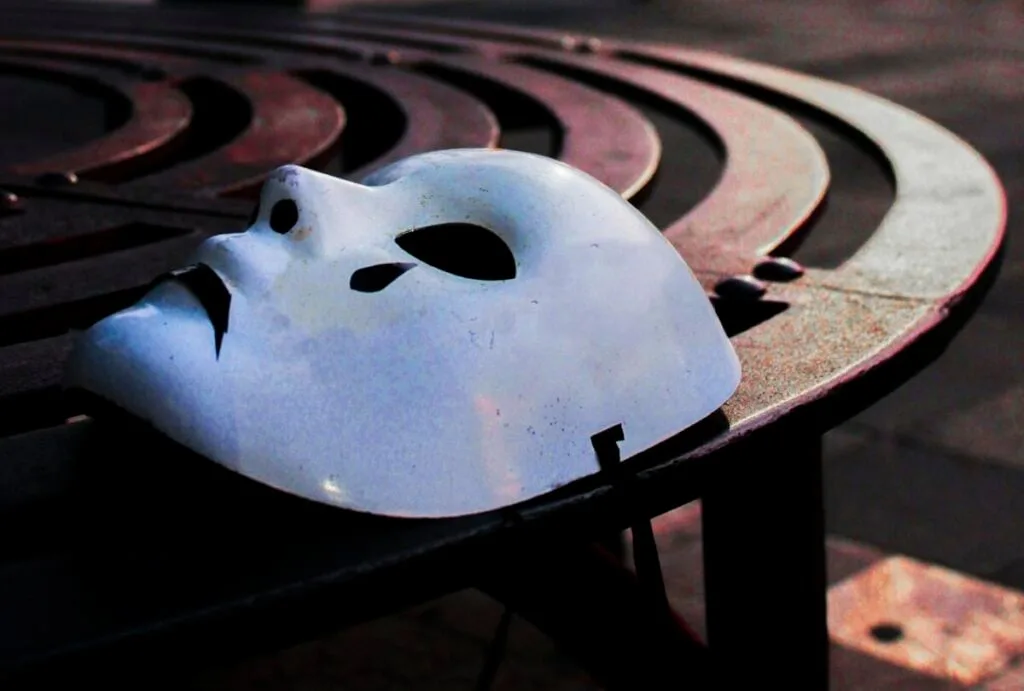 A solitary white mask on a circular bench at dawn in a quiet urban street.
