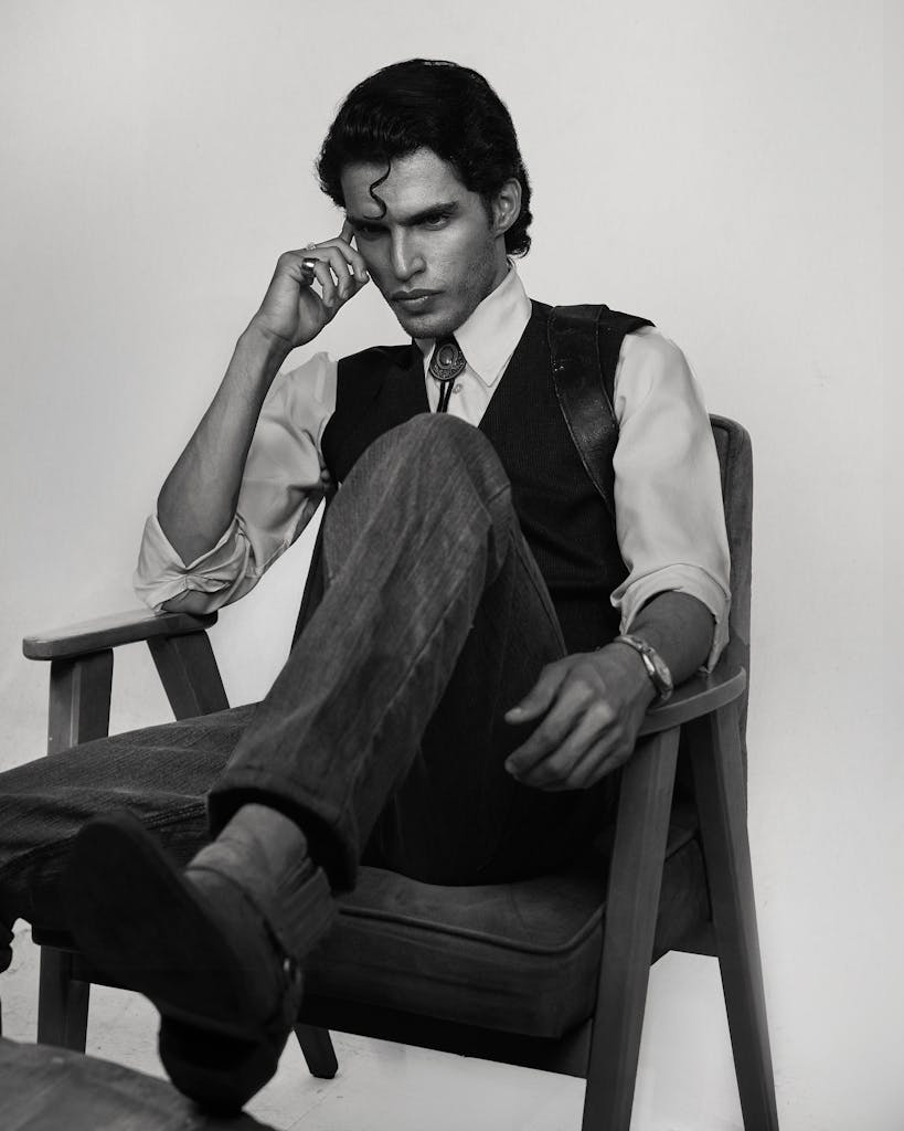 Black and white portrait of a man in deep thought sitting on a chair.