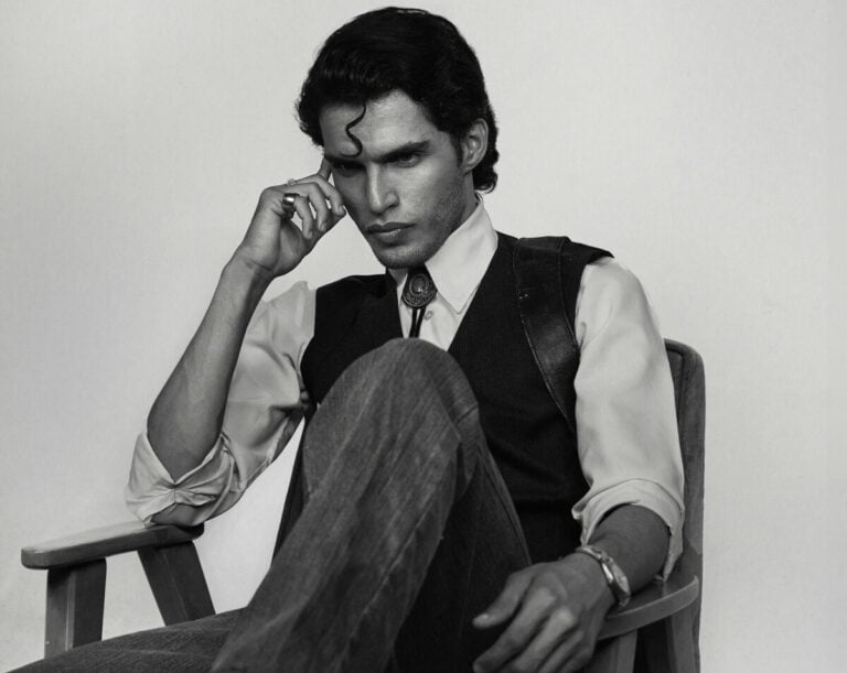 Black and white portrait of a man in deep thought sitting on a chair.