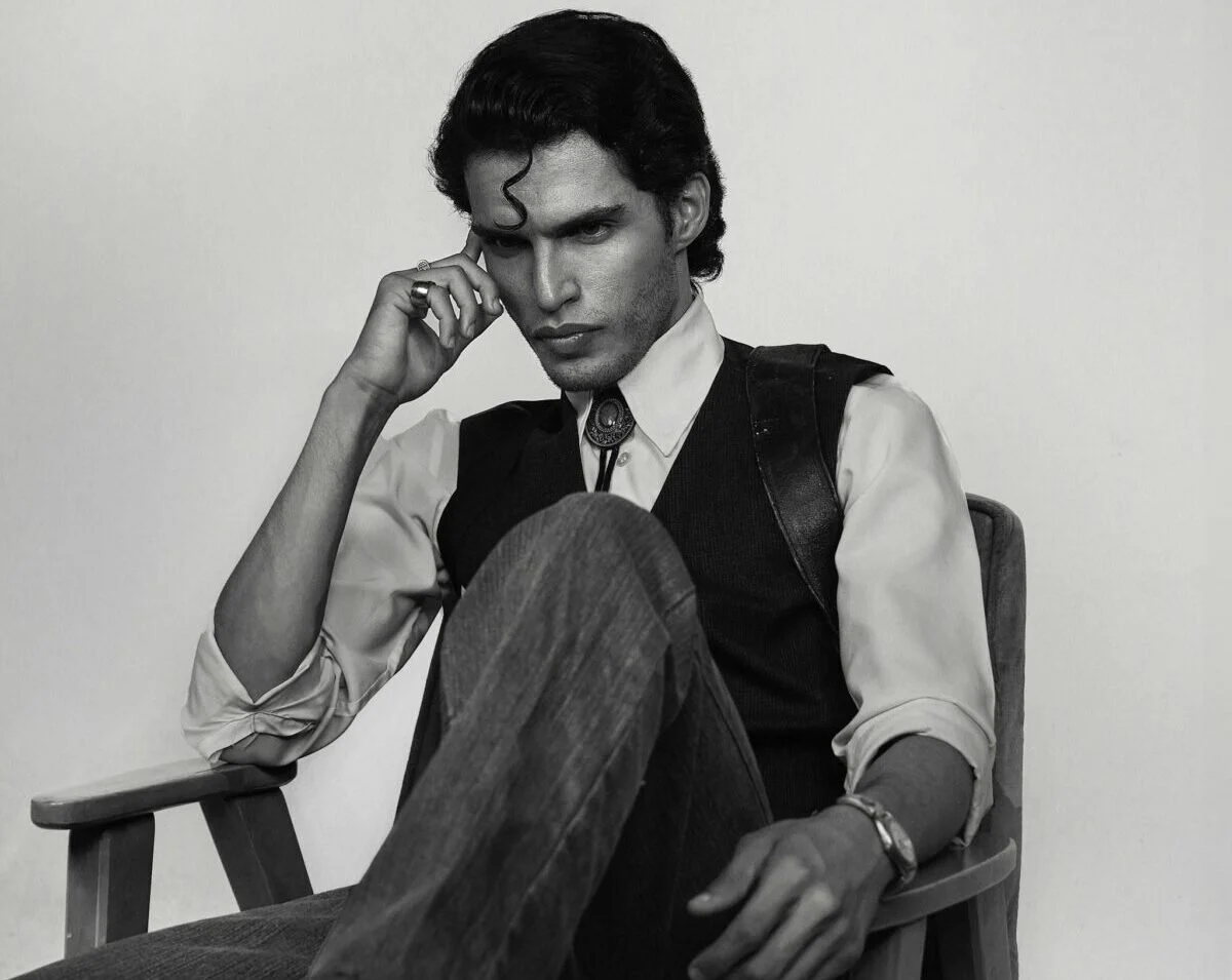 Black and white portrait of a man in deep thought sitting on a chair.