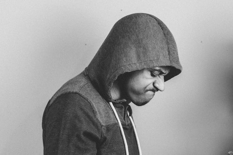 Black and white portrait of a man in a hoodie, expressing frustration.