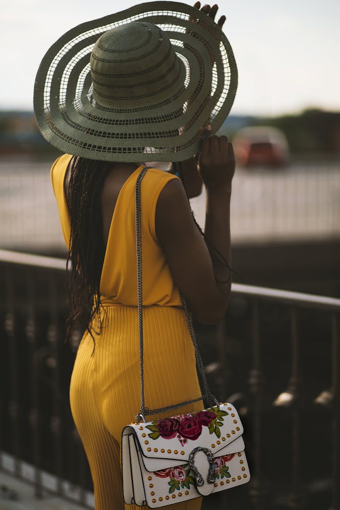 Fashionable woman in summer attire overlooking serene landscape outdoors.