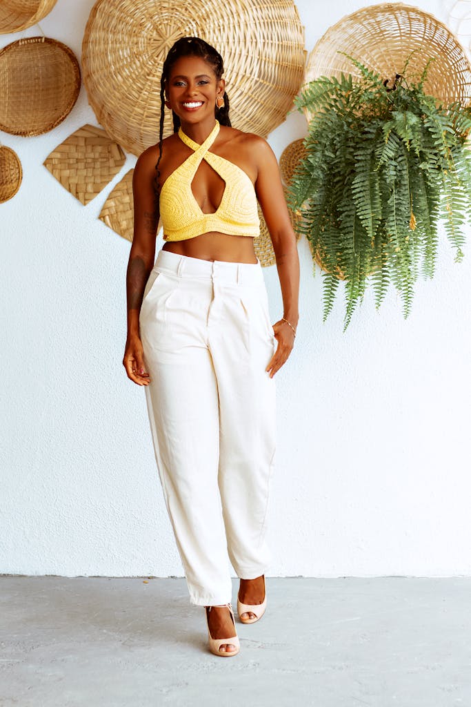 Fashionable woman walking indoors in yellow top and white pants, summer style.