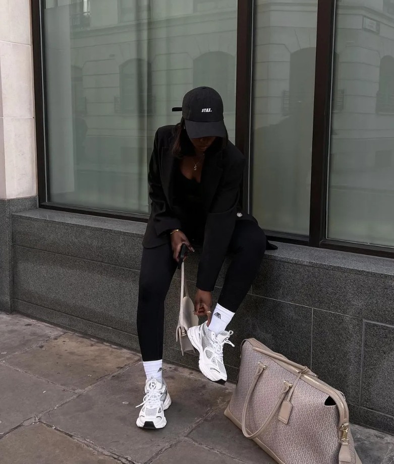 beautiful woman wearing a black top, blazer and leggins, and white sneakers