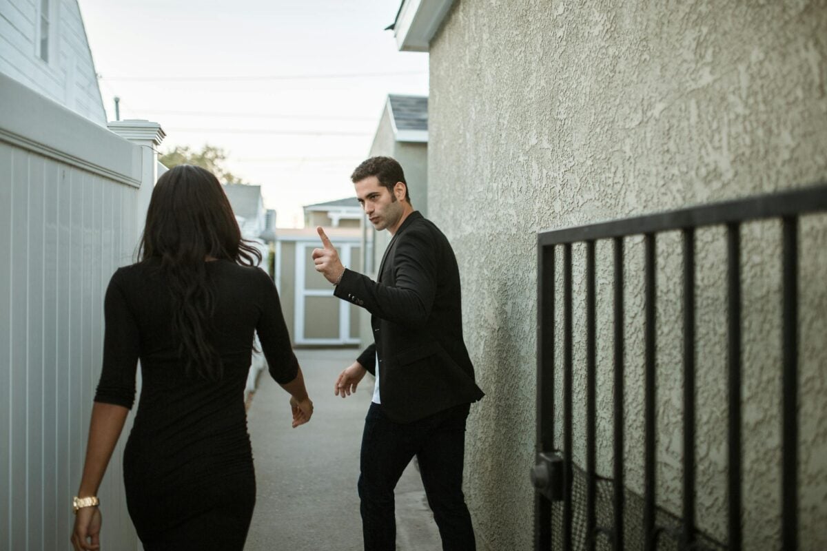 A couple having a tense argument in an outdoor alley, showcasing relationship conflict.
