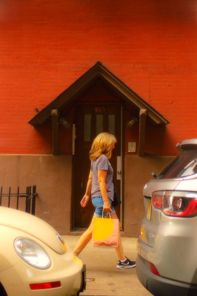 A woman walking on an urban sidewalk holding a shopping bag, illustrating everyday city life.