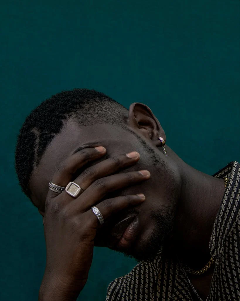 Close-up portrait of a man with hand covering face, showcasing emotional depth and personal reflection.