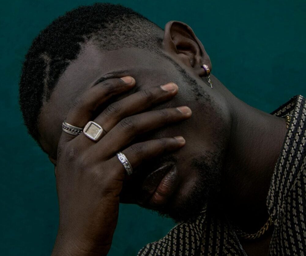 Close-up portrait of a man with hand covering face, showcasing emotional depth and personal reflection.