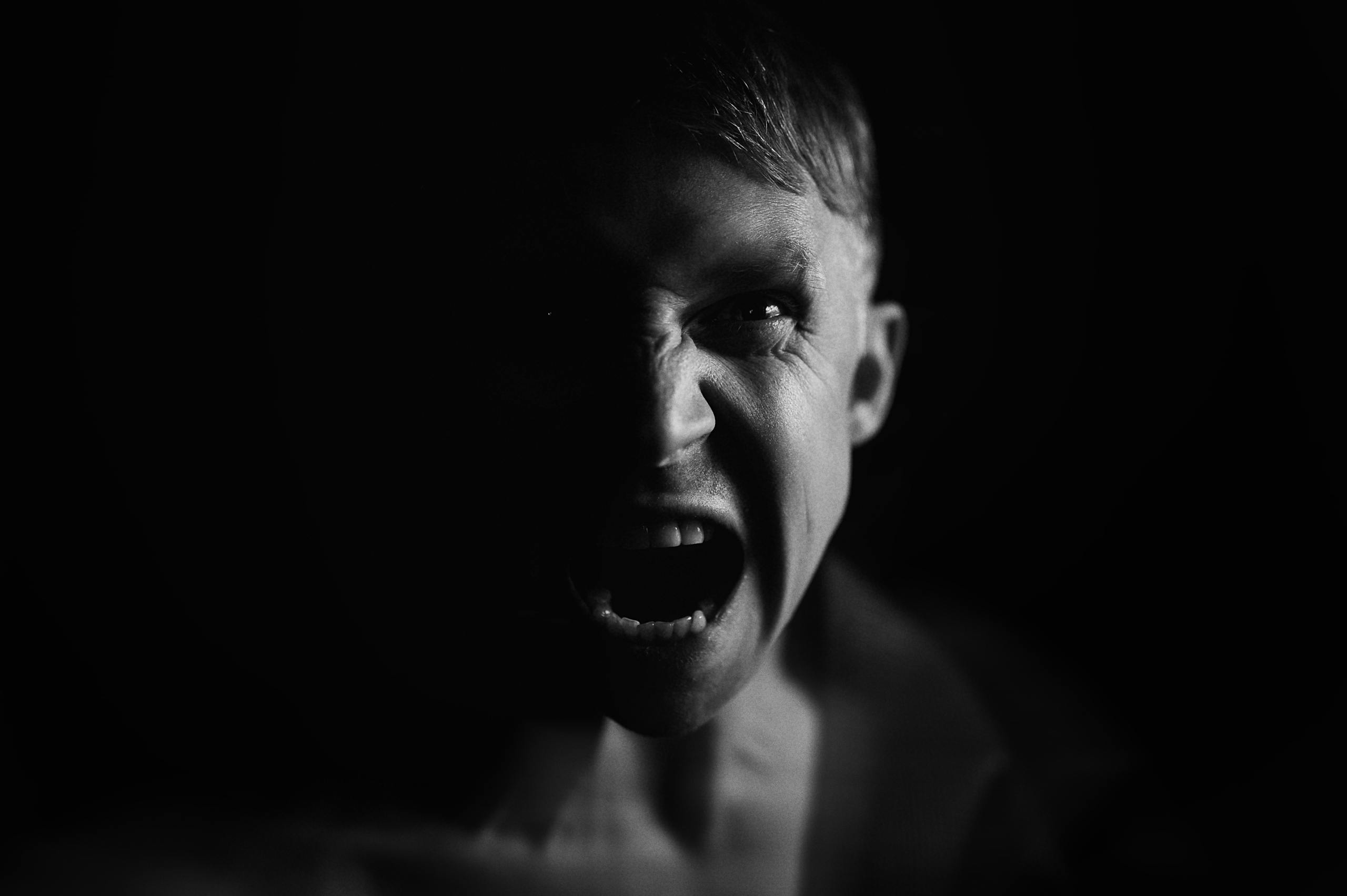 Dramatic black and white portrait capturing a man's intense fury and expressive anger.