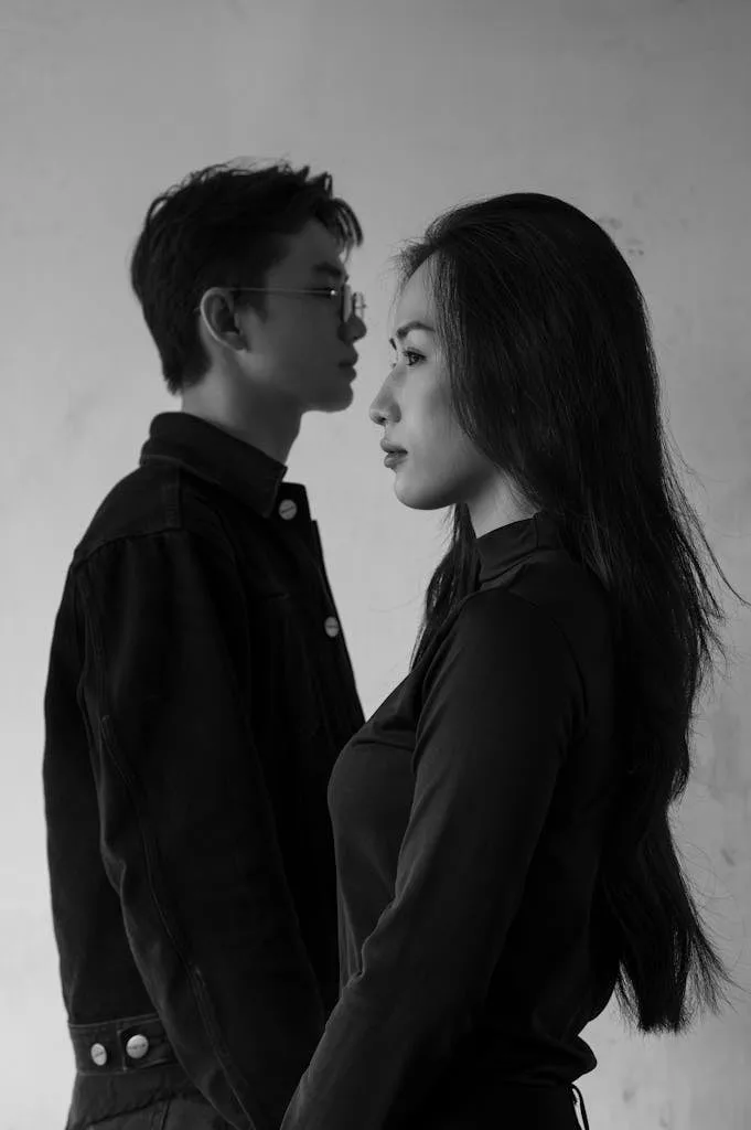 Minimalist black and white portrait of a man and woman in profile view against a plain background.