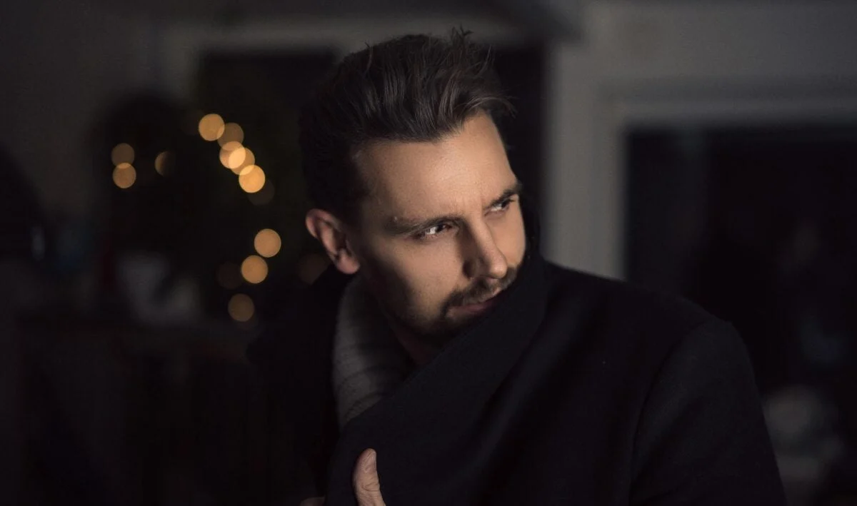 Portrait of a handsome man in a coat indoors with creative lighting and bokeh effect.