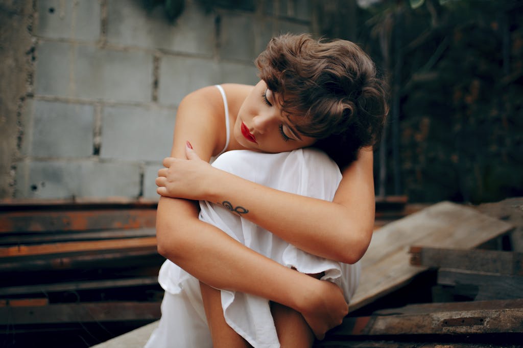 A woman in a white dress sits alone, conveying solitude and introspection.