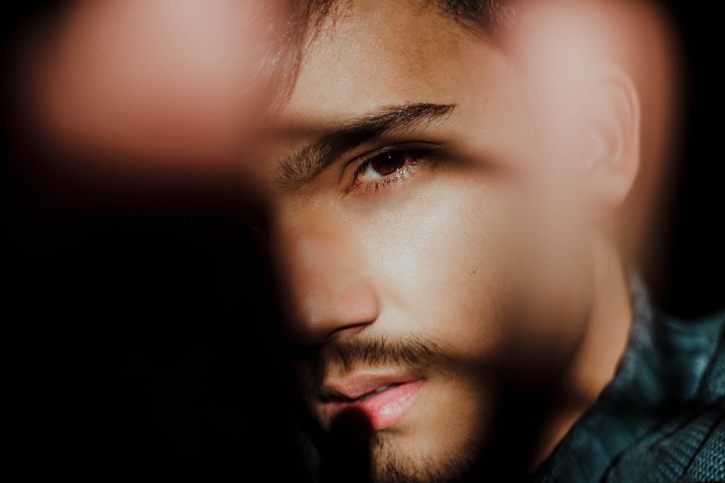 Stylized close-up of a man's face with striking light and shadow contrast.