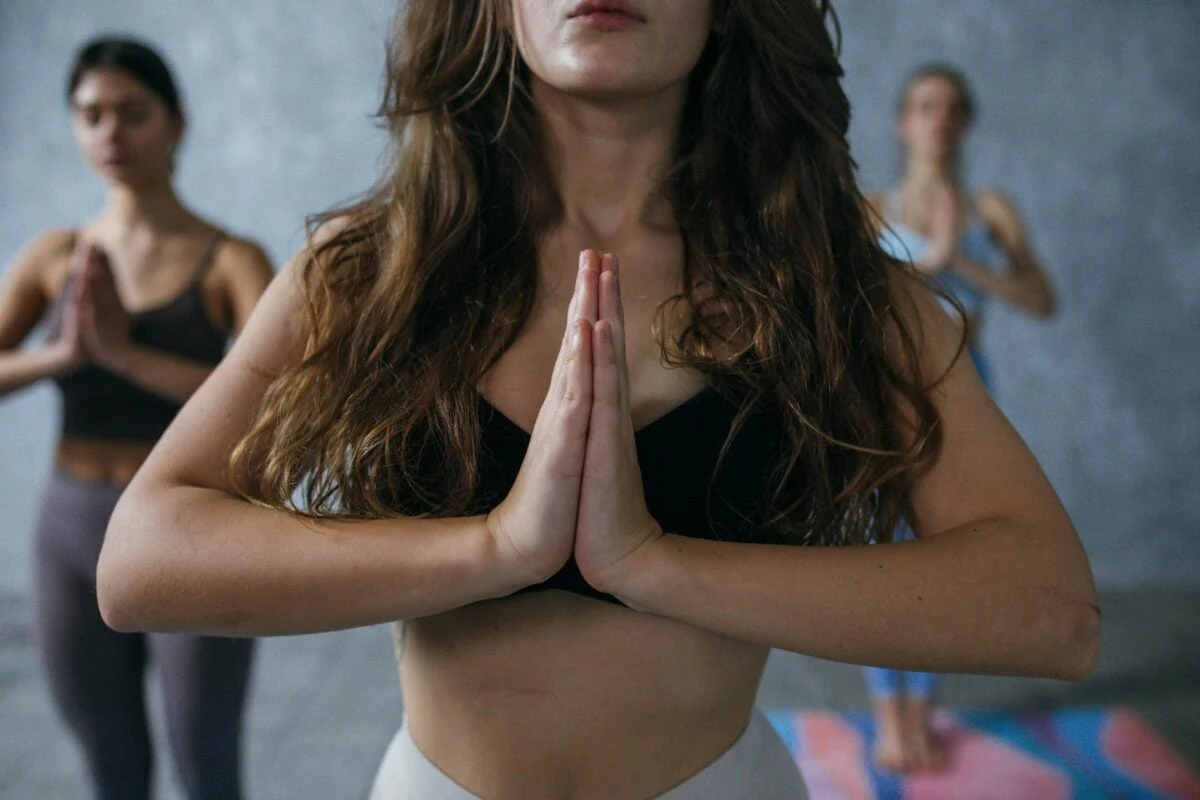 Women practicing yoga in a group indoors, focusing on meditation and relaxation.
