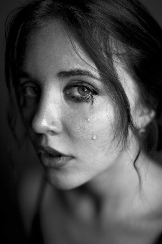 A black and white portrait capturing a woman's emotional expression with tears.