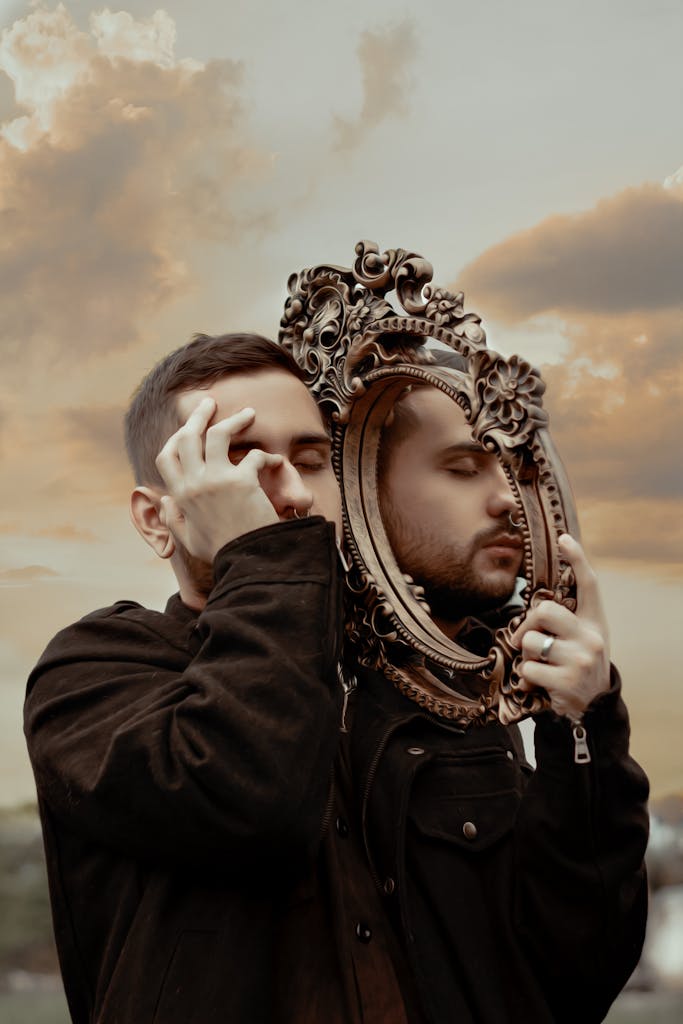 A creative outdoor portrait featuring a man reflecting through an ornate golden frame at sunset.