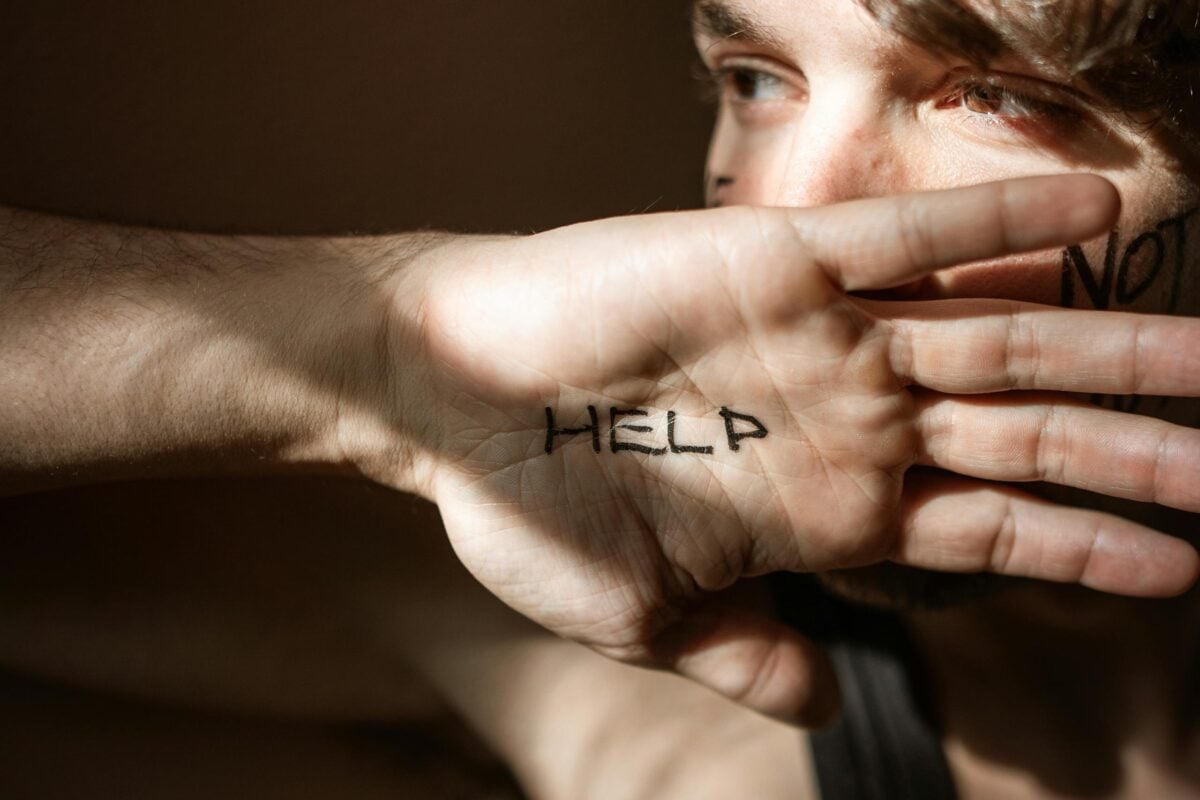 An expressive close-up of a hand with 'Help' written on the palm, symbolizing a need for assistance.