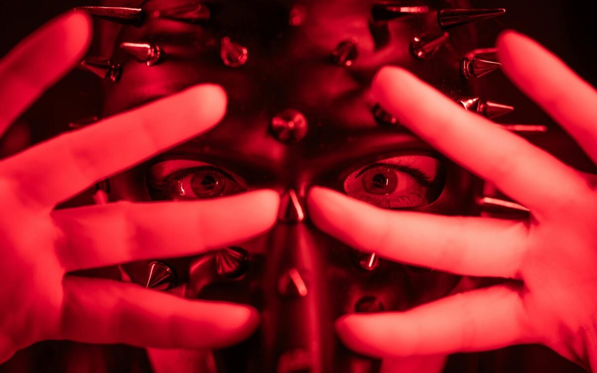 Close-up of a spiked mask in red lighting, evoking mystery and intrigue.