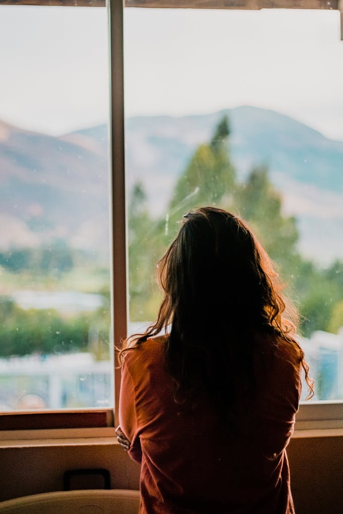 Silhouette of a woman looking out a window at a scenic mountain view in Cajamarca, Peru.