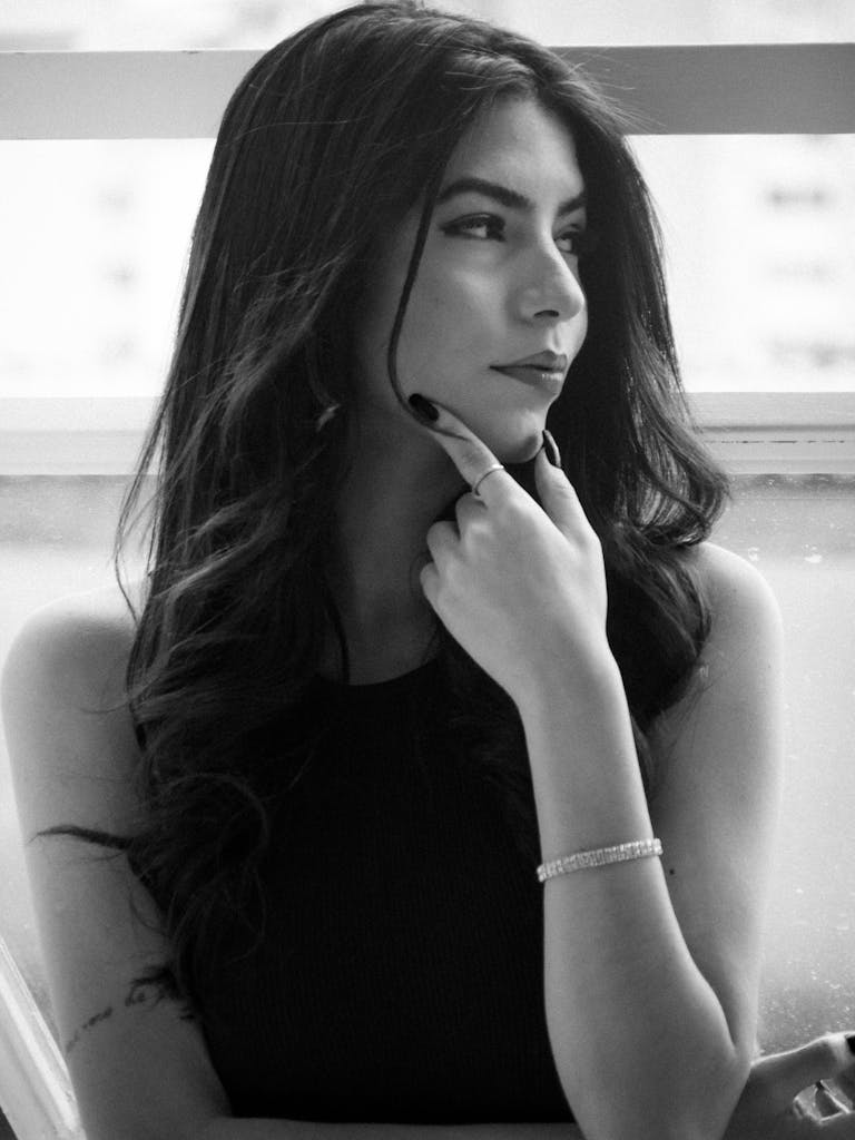 Stylish black and white portrait of an adult woman gazing thoughtfully to the side indoors.