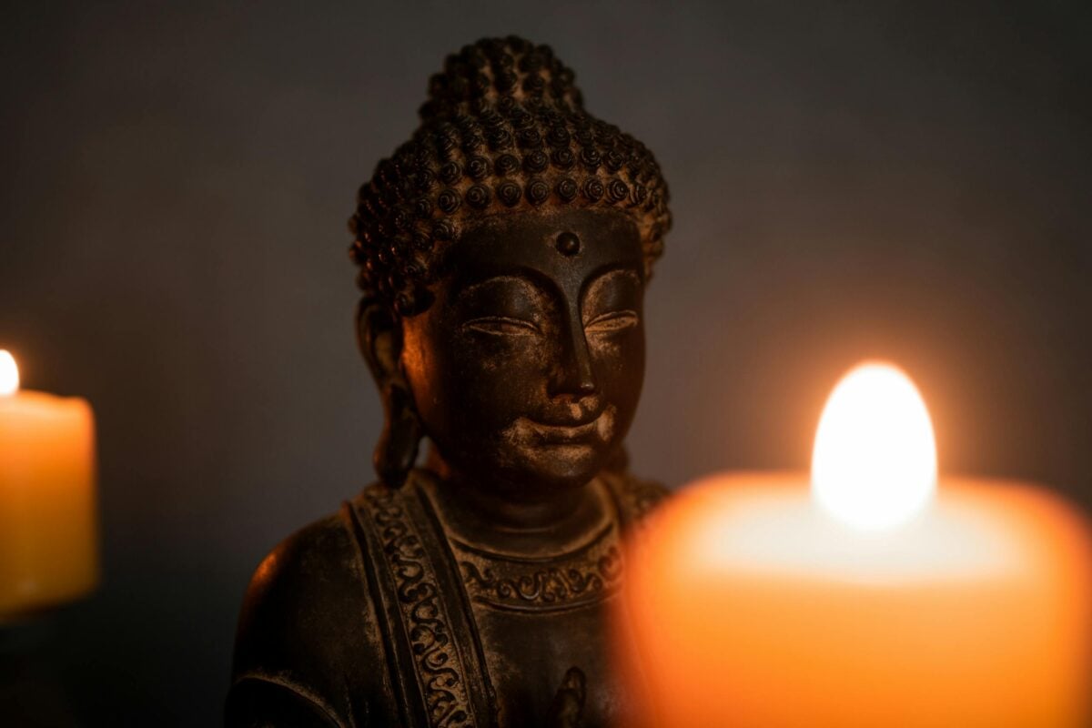 A serene Buddha statue with warm candlelight, evoking tranquility and meditation.