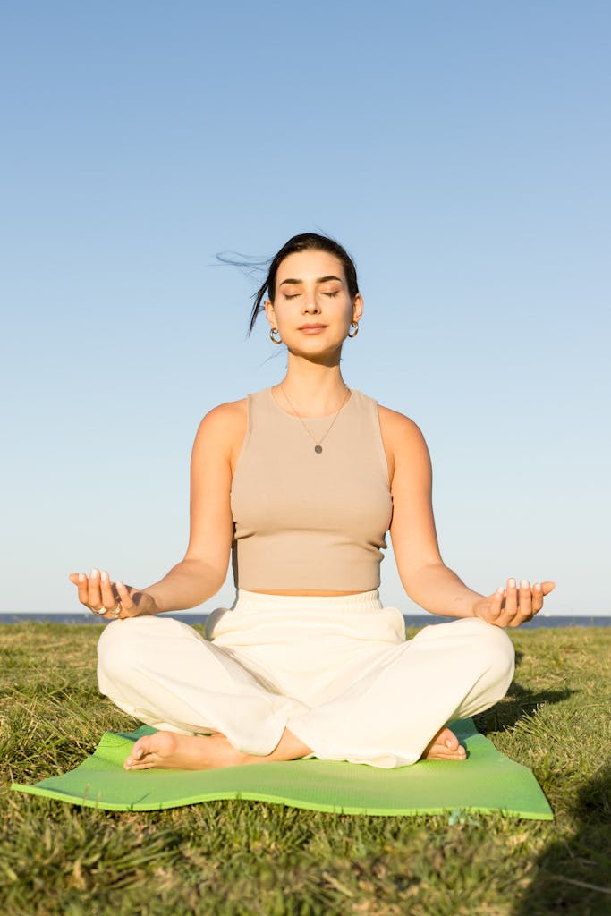 A woman practices meditation and yoga outdoors on a sunny summer day.