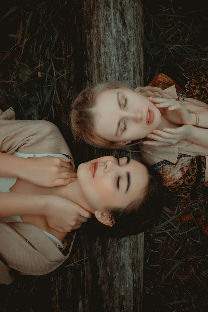 Two women relaxing outdoors, eyes closed, enjoying a peaceful moment in nature.