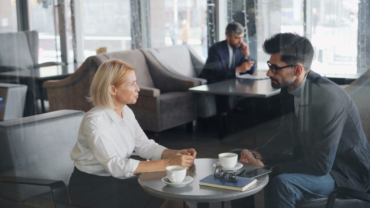 Two coworkers having a business meeting in a cozy caf&eacute;, discussing over coffee.