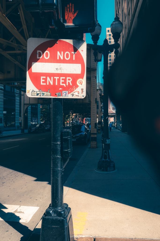 A city street featuring a prominent 'Do Not Enter' sign under bright sun.