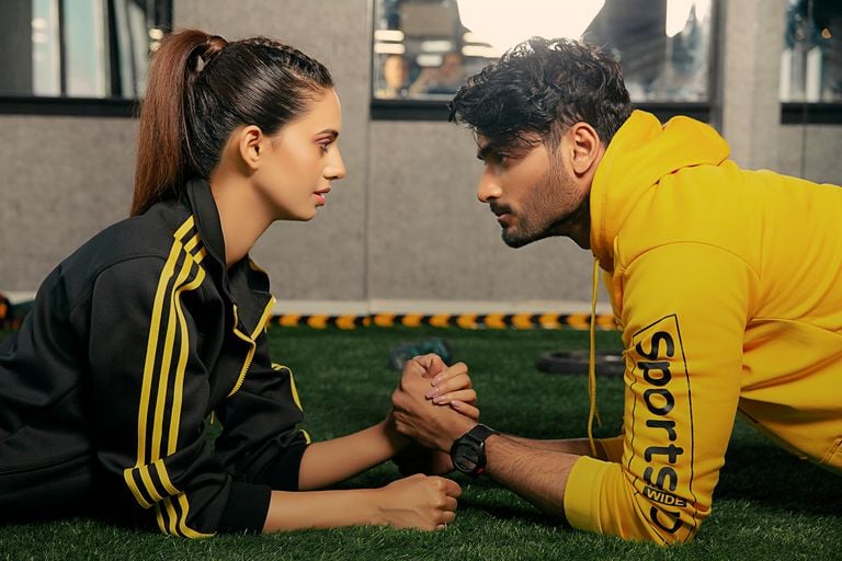 A couple engages in a friendly arm wrestling match at the gym, showcasing fitness and camaraderie.