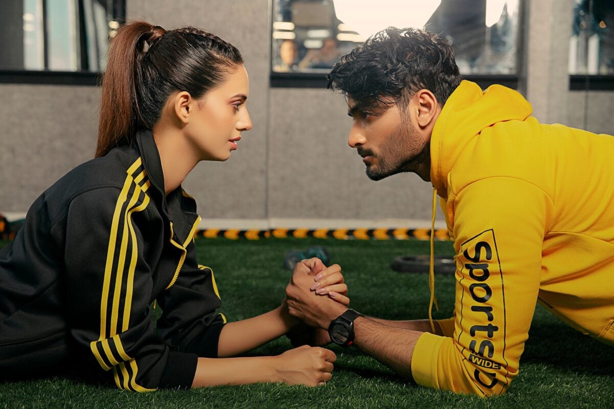 A couple engages in a friendly arm wrestling match at the gym, showcasing fitness and camaraderie.