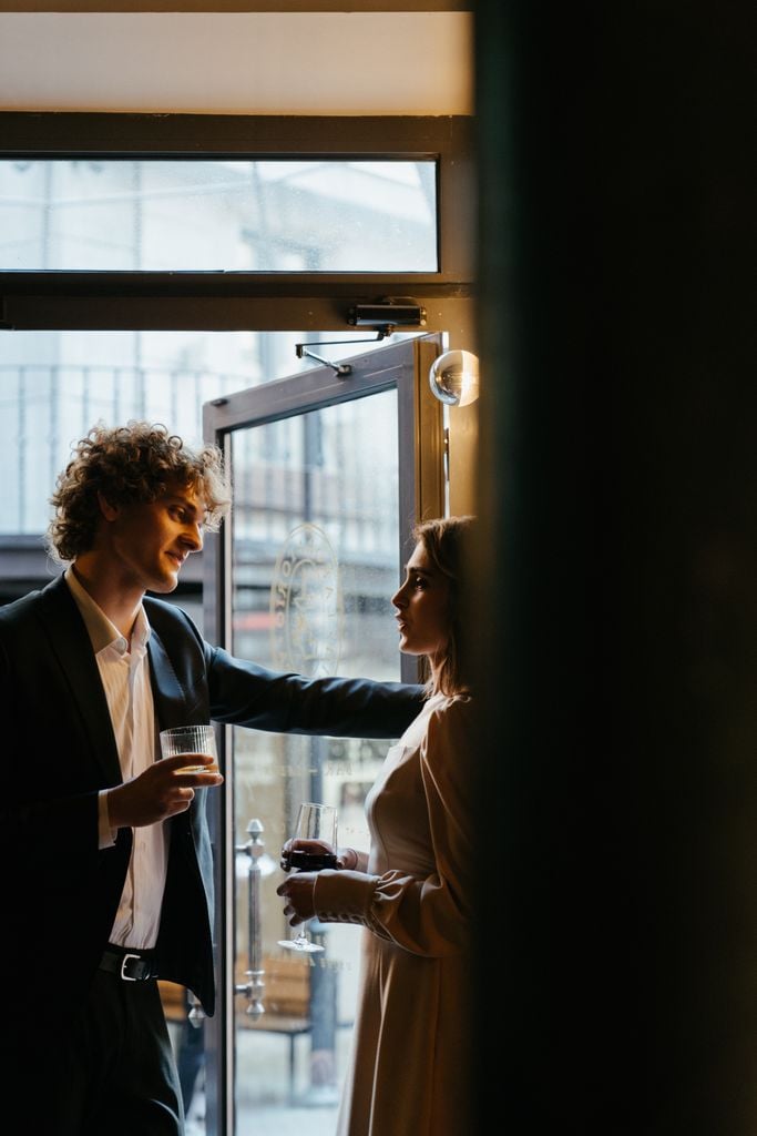 A man and woman enjoying drinks while engaging in a charming conversation in a sophisticated bar.