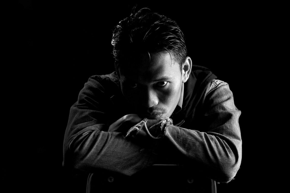 Black and white portrait of a man with intense expression wearing denim jacket.