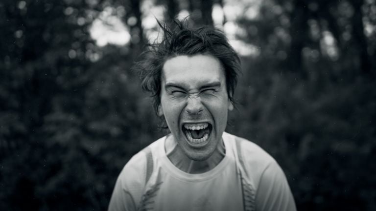 Close-up of a man expressing intense emotion, captured in black and white for a dramatic effect.