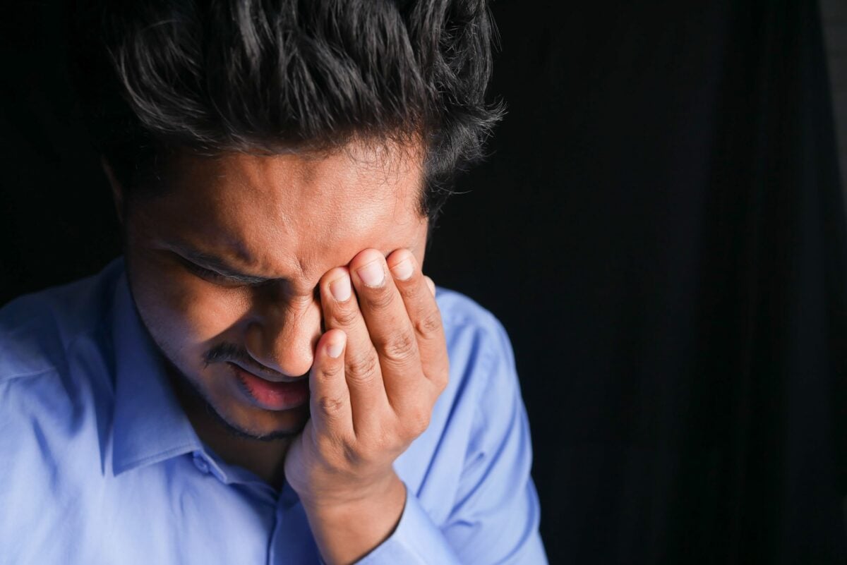 Close-up of a man touching his eye, showing signs of discomfort and pain.