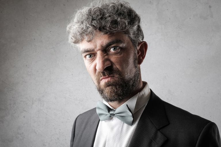 Close-up shot of a serious bearded man in formal wear. Studio photography.