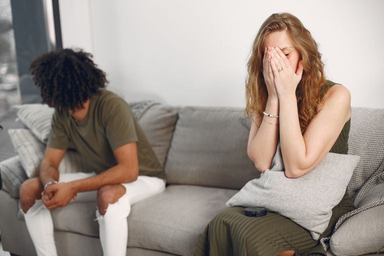 Couple experiencing emotional conflict on a sofa indoors with depth of field effect.