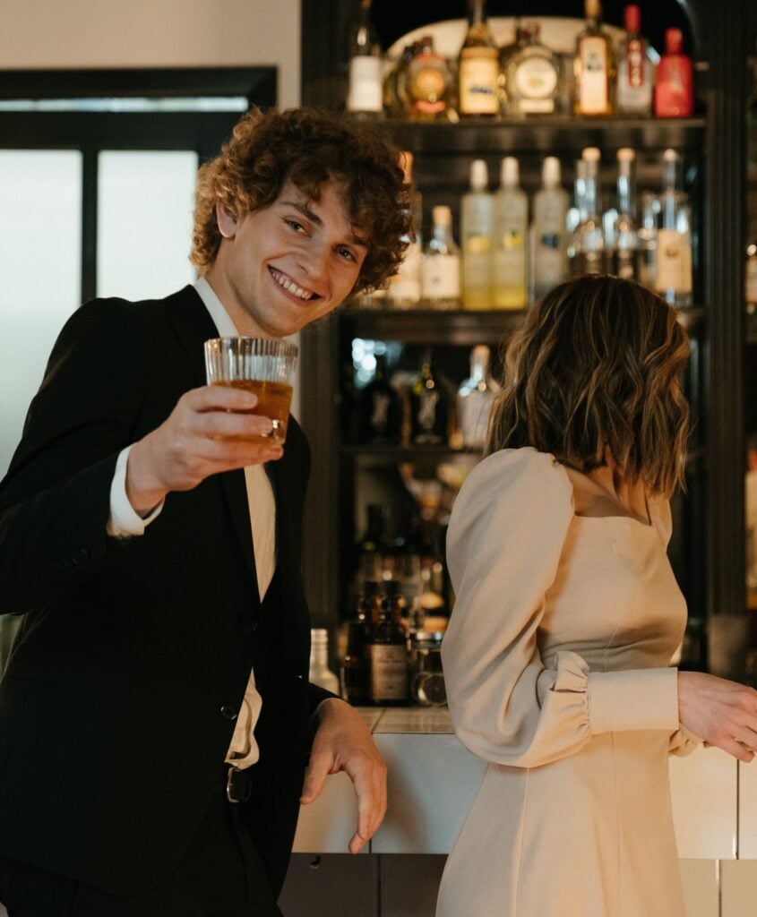 Man and woman enjoying evening drinks at a stylish bar, engaged in cheerful conversation.