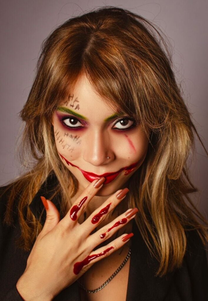 Portrait of a woman in vivid Joker-themed Halloween makeup.