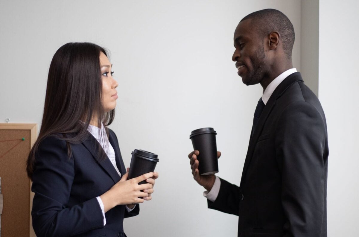 Two colleagues in suits having a coffee conversation during office break.