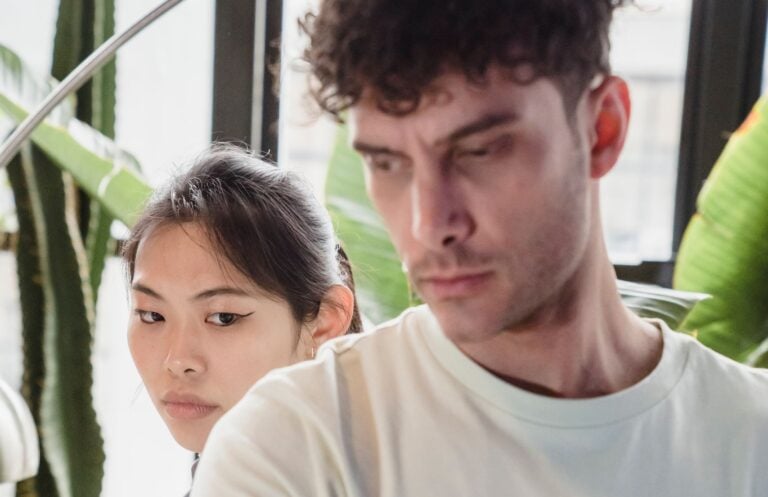 A couple facing away from each other in a tense indoor setting, depicting emotional stress.