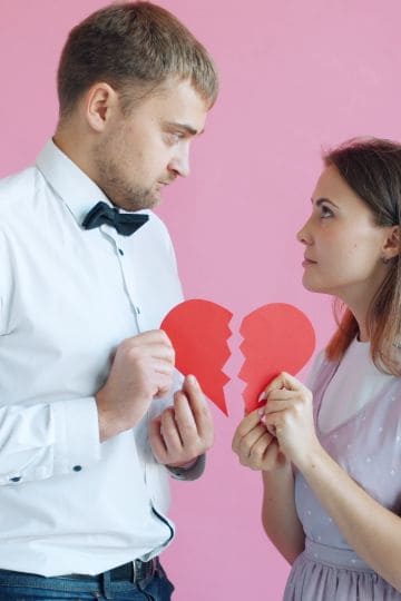 A couple holding a broken heart symbolizing a relationship problem or breakup.