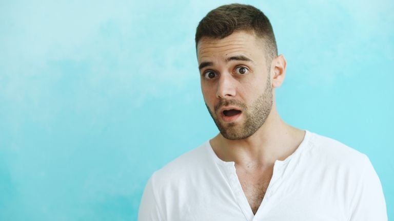 A surprised man in a white shirt with a blue background.